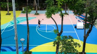 Anak-anak bermain basket di atas mural karya seniman grafiti Stereoflow alias Adi Dharma di Lapangan Taman Menteng, Jakarta Pusat, Rabu (18/10/2022). [Suara.com/Alfian Winanto]