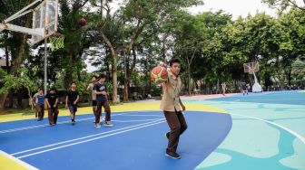 Anak-anak bermain basket di atas mural karya seniman grafiti Stereoflow alias Adi Dharma di Lapangan Taman Menteng, Jakarta Pusat, Rabu (18/10/2022). [Suara.com/Alfian Winanto]