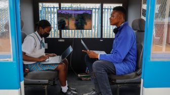 Siswa sekolah menengah teknik Soshanguve menghubungkan laptop ke layar kereta bertenaga surya yang mereka buat, di kotapraja Soshanguve, Pretoria, Afrika Selatan, Selasa (20/10/2022). [Phill Magakoe / AFP]
