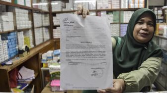 Seorang pedagang menunjukkan surat edaran larangan penjualan obat bebas dalam bentuk sirop di Pasar Pramuka, Jakarta, Jumat (21/10/2022).  ANTARA FOTO/Sulthony Hasanuddin