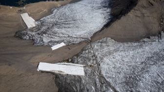 Foto udara menunjukkan selimut yang menutupi es di celah Tsanfleuron untuk mencegahnya mencair di resor Glacier, Les Diablerets, Swiss, Selasa (13/9/2022). [Fabrice COFFRINI / AFP]