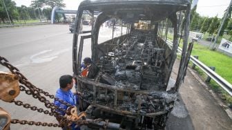 Petugas mengamati bus pariwisata bernopol AE 7388 UG yang terbakar di Gerbang Tol Otomatis (GTO) Menanggal Surabaya, Jawa Timur, Jumat (28/10/2022). [ANTARA FOTO/Umarul Faruq/aww].