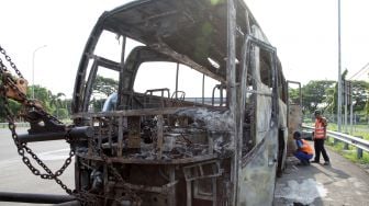 Petugas mengamati bus pariwisata bernopol AE 7388 UG yang terbakar di Gerbang Tol Otomatis (GTO) Menanggal Surabaya, Jawa Timur, Jumat (28/10/2022). [ANTARA FOTO/Umarul Faruq/aww].