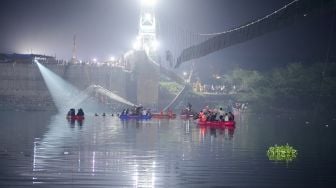 Personel penyelamat melakukan operasi pencarian setelah jembatan di seberang sungai Machchhu runtuh di Morbi, Ahmedabad, India, Senin (31/10/2022). [Sam PANTHAKY / AFP]