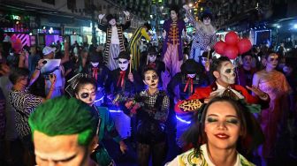 Orang-orang dengan kostum ikut serta dalam parade selama perayaan Halloween di jalan wisata populer Khaosan Road di Bangkok, Thailand, Senin (31/10/2022). [Lillian SUWANRUMPHA / AFP]
