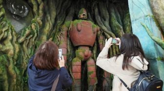 Pengunjung mengambil gambar tentara robot "Tenku no Niwa" di "Ghibli Warehouse" pada hari pertama pembukaan Taman Ghibli di Nagakute, prefektur Aichi, Jepang, Selasa (1/11/2022). [JIJI Press / AFP / Japan OUT]