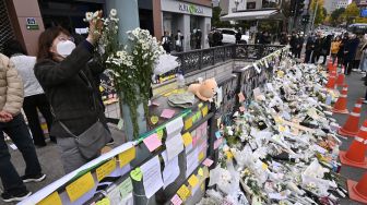 Pelayat menaruh bunga di monumen peringatan darurat untuk para korban Tragedi Itaewon di luar stasiun kereta bawah tanah di distrik Itaewon, Seoul, Korea Selatan, Kamis (3/11/2022). [Jung Yeon-je / AFP]