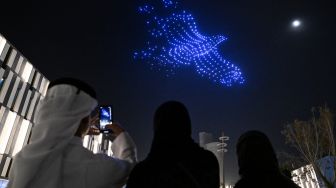  Orang-orang melihat pertunjukan drone di Lusail, Qatar, Sabtu (5/11/2022). [Kirill KUDRYAVTSEV / AFP]