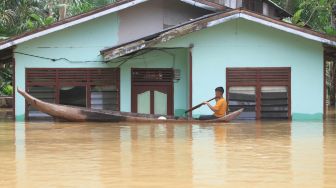 Seorang anak naik perahu saat melintasi banjir di Desa Napai, Woyla Barat, Aceh Barat, Aceh, Sabtu (5/11/2022). [ANTARA FOTO/Syifa Yulinnas/wsj]
