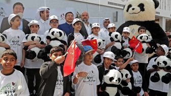 Anak-anak membawa boneka panda saat berswafoto di Panda House di Al Khor, Qatar, Rabu (19/10/2022). [DENOUR/AFP]
