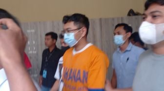 Pemeran pria di video mesum wanita kebaya merah, berinisial ACS berjalan di Mapolda Jatim, Surabaya, Selasa (8/11/2022). [Suara.com/ Yuliharto Simon]