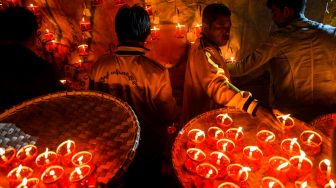 Orang-orang yang mempersiapkan lentera untuk dipasang pada balon udara selama Festival Cahaya Tazaungdaing di Pyin Oo Lwin, Mandalay, Myanmar, Minggu (6/11/2022). [AFP]