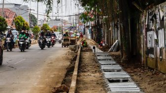 Pekerja menyelesaikan proyek revitalisasi trotoar di Jalan Dewi Sartika, Depok, Jawa barat, Rabu (9/11/2022). [Suara.com/Alfian Winanto]