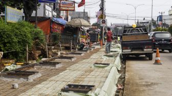 Pekerja menyelesaikan proyek revitalisasi trotoar di Jalan Dewi Sartika, Depok, Jawa barat, Rabu (9/11/2022). [Suara.com/Alfian Winanto]