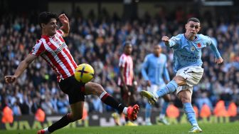 Gelandang Manchester City Phil Foden (kanan) menembak bola tetapi gagal mencetak gol saat pertandingan sepak bola Liga Premier Inggris antara Manchester City dan Brentford di Stadion Etihad, Manchester, Inggris, Sabtu (12/11/2022). [Oli SCARFF / AFP] 
