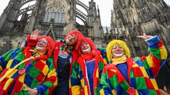 Orang-orang berswafoto di depan katedral untuk merayakan dimulainya musim Karnaval musim karnaval "kelima" atau karnaval konyol di Cologne, Jerman, Jumat (11/11/2022). [INA FASSBENDER / AFP]