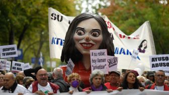 Para pengunjuk rasa membawa patung yang menggambarkan presiden daerah Isabel Diaz Ayuso selama demonstrasi yang diserukan untuk perbaikan sistem kesehatan di Madrid, Spanyol, Minggu (13/11/2022). [OSCAR DEL POZO / AFP]
