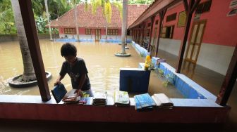 Seorang anak menata buku yang basah terkena banjir di Sekolah Dasar Negeri 2 Krakitan, Bayat, Klaten, Jawa Tengah, Rabu (16/11/2022). [ANTARA FOTO/Aloysius Jarot Nugroho/foc].