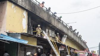 Petugas pemadam kebakaran melakukan proses pendinginan saat kebakaran melanda kios pertokoan Pasar Pagi Asemka di Jakarta, Jumat (18/11/2022). [ANTARA FOTO/Muhammad Adimaja/rwa].