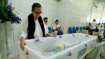 Istri Rudis Salam,  Marina Gardena berada disamping peti jenazah, Jakarta, Jumat (18/11). [Suara.com/Oke Atmaja]