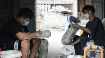 Pekerja membuat model plester trofi Piala Dunia di sebuah lokakarya di Hanoi, Vietnam, Rabu (16/11/2022). [Nhac NGUYEN / AFP]