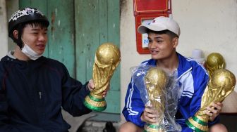 Fans membeli model plester trofi Piala Dunia FIFA di sebuah lokakarya di Hanoi, Vietnam, Rabu (16/11/2022). [Nhac NGUYEN / AFP]
