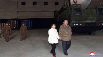 Pemimpin Korea Utara Kim Jong Un (kanan) berjalan dengan putrinya saat memeriksa rudal balistik antarbenua (ICBM) baru "Hwasong Gun 17" di Bandara Internasional Pyongyang, Korea Utara, Jumat (18/11/2022). [KCNA VIA KNS/AFP]