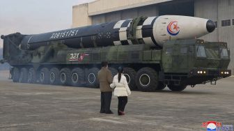 Pemimpin Korea Utara Kim Jong Un (kanan) berjalan dengan putrinya saat dia memeriksa rudal balistik antarbenua (ICBM) baru "Hwasong Gun 17" di Bandara Internasional Pyongyang, Korea Utara, Jumat (18/11/2022). [KCNA VIA KNS/AFP]