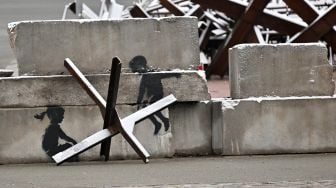 Grafiti karya seniman jalanan Inggris Banksy di sebuah konstruksi anti-tank yang tertutup salju di Independence Square di Kyiv, Ukraina, Kamis (17/11/2022). [Sergei SUPINSKY / AFP]
