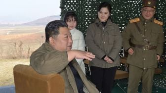 Pemimpin Korea Utara Kim Jong Un (kiri), bersama istrinya Ri Sol Ju (kedua kanan) dan putrinya (kedua kiri) saat mereka menghadiri uji coba rudal balistik antarbenua (ICBM) baru tipe "Hwasong Gun 17" di sebuah lokasi yang dirahasiakan di Korea Utara, Jumat (18/11/2022). [KCNA VIA KNS/AFP]
