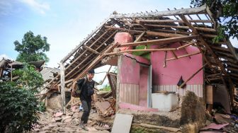 Warga melintas di depan rumah yang roboh akibat gempa di Kampung Selakawung Tengah, Kabupaten Cianjur, Jawa Barat, Selasa (22/11/2022). [ANTARA FOTO/Raisan Al Farisi/foc].