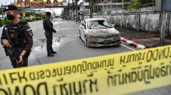 Petugas polisi berdiri di dekat mobil yang rusak sebagian setelah bom mobil meledak di kota Narathiwat, Thailand, Selasa (22/11/2022). [Madaree TOHLALA / AFP]