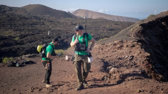 Astronot Jerman Alexander Gerst (kanan) berjalan di puncak gunung berapi purba selama program pelatihan untuk mempelajari cara menjelajahi Bulan dan Mars di Taman Nasional Timanfaya Pulau Lanzarote, Kepulauan Canary, Spanyol, Selasa (10/11/2022). [DESIREE MARTIN / AFP]