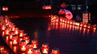Seorang penduduk setempat melihat lilin yang dipajang untuk memperingati para korban Holodomor 1932-1933 di Lviv, Ukraina, Sabtu (26/11/2022). [YURIY DYACHYSHYN / AFP]
