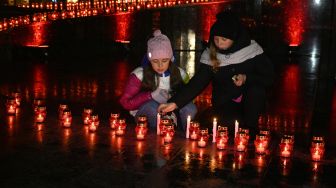 Anak-anak menyalakan lilin untuk memperingati para korban Holodomor 1932-1933 di Lviv, Ukraina, Sabtu (26/11/2022). [YURIY DYACHYSHYN / AFP]