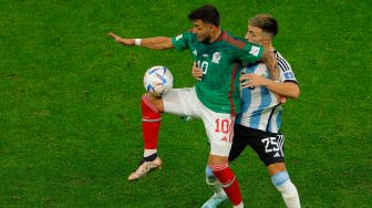 Penyerang Meksiko Alexis Vega (kiri) berebut bola dengan bek Argentina Lisandro Martinez (kanan) saat pertandingan sepak bola Grup C Piala Dunia 2022 antara Argentina dan Meksiko di Stadion Lusail di Lusail, Qatar, Sabtu (26/11/2022). [Odd ANDERSEN/AFP]