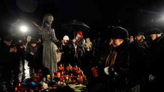 Penduduk setempat menghadiri upacara di monumen para korban Holodomor di Kyiv, Ukraina, Sabtu (26/11/2022). [Sergei CHUZAVKOV / AFP]