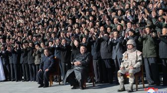 Pemimpin Korea Utara Kim Jong Un (duduk di tengah) dan putrinya (berdiri di tengah) foto bersama dengan para ilmuwan, insinyur, pejabat militer dan para pekerja di pabrik amunisi yang berkontribusi dalam uji coba rudal balistik antarbenua (ICBM) Hwasong-17 di lokasi rahasia, dalam foto tak bertanggal yang rilis pada Minggu (27/11/2022). [KCNA VIA KNS / AFP]