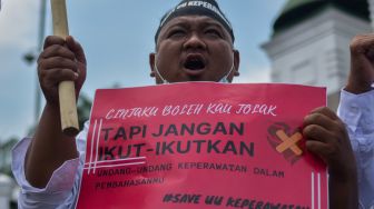 Seorang tenaga kesehatan membawa poster saat berunjuk rasa menolak RUU Omnibuslaw Kesehatan di depan Gedung Parlemen, Senayan, Jakarta, Senin (28/11/2022). [ANTARA FOTO/Sulthony Hasanuddin/wsj]