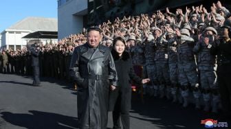 Pemimpin Korea Utara Kim Jong Un (kiri) dan putrinya (kanan) memberi selamat kepada tentara yang berkontribusi pada uji coba rudal balistik antarbenua (ICBM) di lokasi rahasia, dalam foto tak bertanggal yang rilis pada Minggu (27/11/2022). [KCNA VIA KNS / AFP]