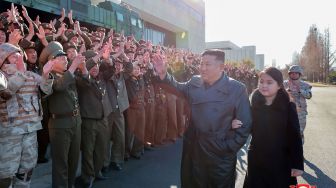 Pemimpin Korea Utara Kim Jong Un (kedua dari kanan) dan putrinya (kanan) memberi selamat kepada tentara yang berkontribusi pada uji coba rudal balistik antarbenua (ICBM) di lokasi rahasia, dalam foto tak bertanggal yang rilis pada Minggu (27/11/2022). [KCNA VIA KNS / AFP]