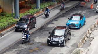 Kendaraan melintasi jalan rusak di sekitar Pembangunan Stasiun LRT, Jalan Rasuna Said, Jakarta Selatan, Rabu (30/11/2022). [Suara.com/Alfian Winanto]