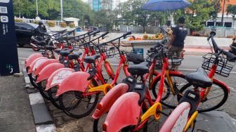 Warga melintas melintas di dekat sepeda sewa yang terparkir di Pasar Baru, Jakarta Pusat, Rabu (30/11/2022). [Suara.com/Alfian Winanto]