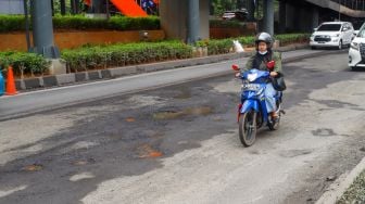 Kendaraan melintasi jalan rusak di sekitar Pembangunan Stasiun LRT, Jalan Rasuna Said, Jakarta Selatan, Rabu (30/11/2022). [Suara.com/Alfian Winanto]