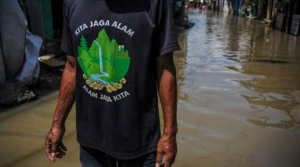 Seorang warga melintasi banjir luapan Sungai Citarum di Kampung Bojongasih, Dayeuhkolot, Kabupaten Bandung, Jawa Barat, Sabtu (3/12/2022). [ANTARA FOTO/Raisan Al Farisi].