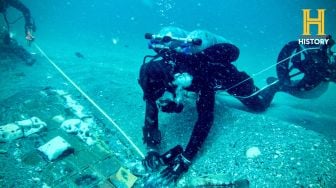 Tim ekspedisi bawah laut dan ahli biologi kelautan Mike Barnette dan penyelam Jimmy Gadomski menjelajahi pecahan sepanjang dua puluh kaki dari Space Shuttle Challenger 1986 yang ditemukan di perairan lepas pantai Florida selama pembuatan film dari seri baru "The Bermuda Triangle: Into Cursed Waters", Kamis (10/12/2022). [Handout / The History Channel / AFP]
