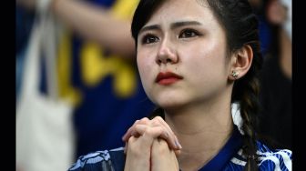 Pendukung Jepang terlihat sedih setelah timnya kalah dalam pertandingan sepak bola babak 16 besar Piala Dunia 2022 antara Jepang dan Kroasia di Stadion Al-Janoub di Al-Wakrah, selatan Doha, Qatar, Senin (5/12/2022). [Jewel SAMAD/AFP]