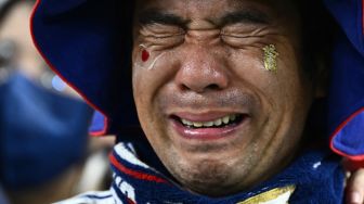 Seorang pendukung Jepang menangis setelah timnya kalah dalam pertandingan sepak bola babak 16 besar Piala Dunia 2022 antara Jepang dan Kroasia di Stadion Al-Janoub di Al-Wakrah, selatan Doha, Qatar, Senin (5/12/2022). [Permata SAMAD / AFP]