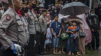 Istri bersama anak almarhum Aiptu Anumerta Sofyan menangis saat upacara serah terima untuk pemakaman secara kedinasan di rumah duka kawasan Cibogo, Bandung, Jawa Barat, Rabu (7/12/2022). [ANTARA FOTO/Novrian Arbi].