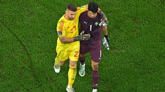 Kiper Spanyol Unai Simon menyapa kiper Maroko Yassine Bounou pada akhir pertandingan sepak bola babak 16 besar Piala Dunia Qatar antara Maroko dan Spanyol di Education City Stadium di Al-Rayyan, barat Doha, Qatar, Selasa (6/12/2022). [MANAN VATSYAYANA/AFP]